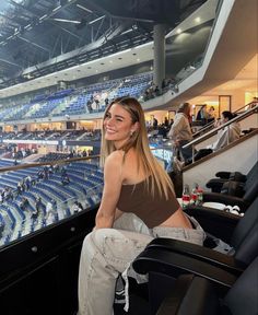 a woman sitting in a chair at a hockey game looking into the camera and smiling