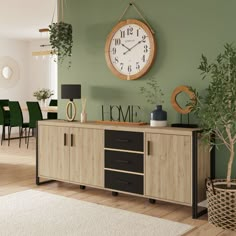 a large clock mounted to the side of a green wall next to a wooden cabinet