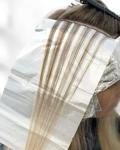 a close up of a woman's head with long hair and scissors in it