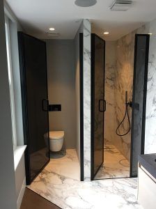 a bathroom with marble walls and flooring next to a toilet in the shower stall