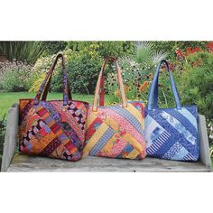 three colorful bags sitting on top of a cement bench