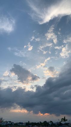 an airplane is flying in the sky with clouds above it and some buildings on the other side