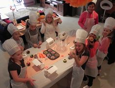 a group of children standing around a table with cupcakes on it