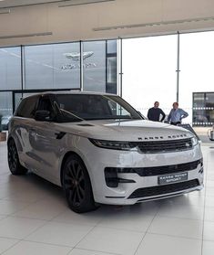 the white range rover is parked in front of two men