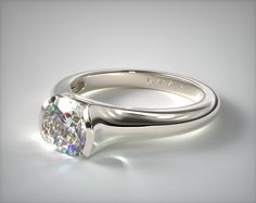 a white gold ring with a round brilliant cut diamond in the center, on a gray background