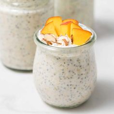 two jars filled with oatmeal and fruit on top of a white table