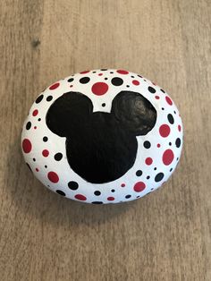 a rock with a mickey mouse face painted on it, sitting on a table top