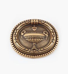 a brass plate with an ornate design on the front and back side, set against a white background