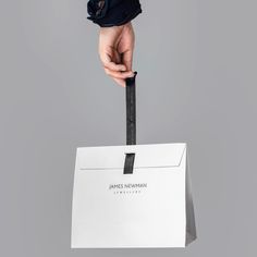 a person's hand holding a white bag with the name james rowan on it