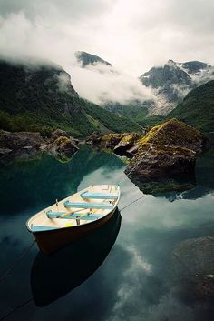 there is a boat that is sitting on the water in the middle of some mountains