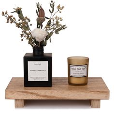 a candle and vase with flowers on a wooden shelf next to a small glass jar