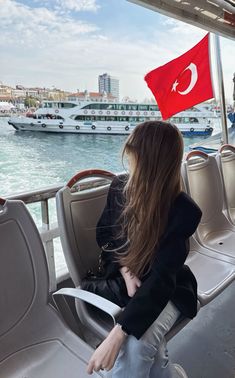 a woman sitting on the back of a boat with a flag flying above her head