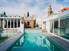 a man standing next to a swimming pool on top of a wooden floored patio