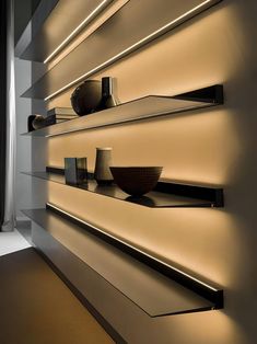 some shelves with bowls and vases on them are lit up by light from the window