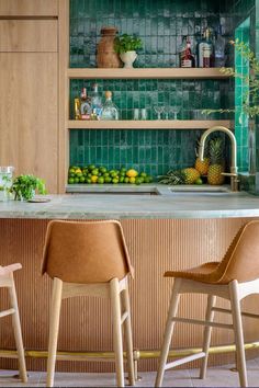 A kitchen features a glistening green zellige wall with wooden cabinetry and tan leather counter stools. Roof Tiles Design, Tommy Bahama Kitchen, Zia Tile, Moroccan Architecture, Tiles Design, Roof Tiles, Kitchen Tile, Outdoor Kitchen Design, Architecture And Design