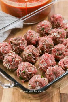 raw meatballs in a glass dish next to a red sauce