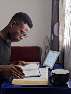 a man sitting at a table with an open book and notebook in front of him