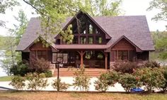 a large house sitting on top of a lush green field next to a lake and forest