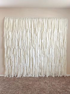 a white curtain is hanging on the wall in front of a carpeted floor and beige walls