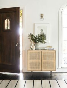 a room with a wooden door and some plants on the sideboard next to it