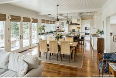 a large open concept kitchen and dining room with wood flooring, white walls and ceiling