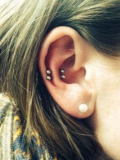 a close up of a person's ear with two piercings