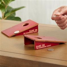 two red game pieces on a table with one being thrown to the other by someone's hand