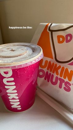 a pink dunkin donuts cup sitting next to a bag