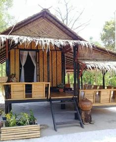 a small hut made out of wood and thatched roof with plants in the foreground