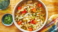 a bowl of chicken noodle soup with carrots and parsley