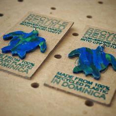 two blue sea turtle earrings are sitting on top of a piece of cardboard with the words reptiles retrieving into omnica