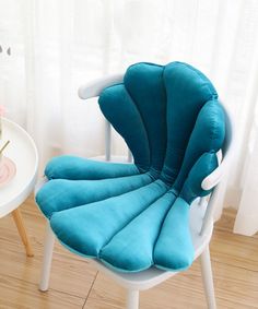 a blue chair sitting on top of a hard wood floor next to a white table