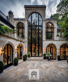 a large building with lots of windows and plants in the front yard, surrounded by stone pavers