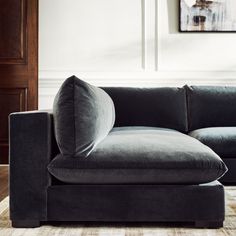 a gray couch sitting on top of a wooden floor next to a painting hanging above it