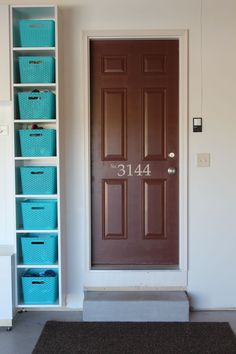 the front door is painted brown and has blue baskets on it, along with white drawers