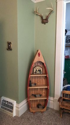 a boat shaped shelf in the corner of a room with antlers on the wall