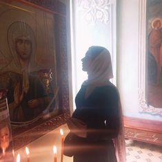 a woman standing in front of a painting with candles