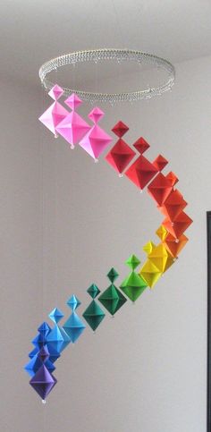 an origami mobile hanging from the ceiling in a room filled with white walls