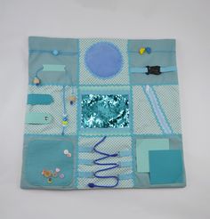 a blue and white patchwork quilt with various items on the front, including scissors, buttons, beads, and other things