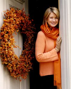 a woman in an orange sweater and black pants standing at the door