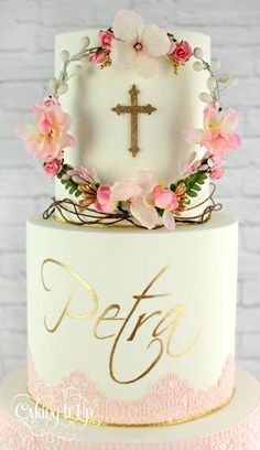 a white cake with pink flowers and a cross on top that says pefty