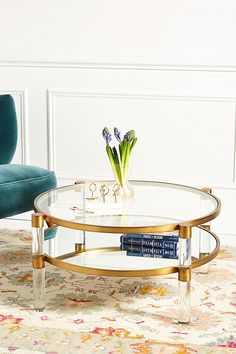 a living room with a blue chair and a glass coffee table in front of a white wall