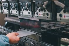 a person is holding a piece of metal in front of some ovens that are lined up