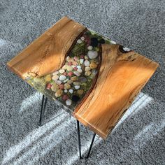 a wooden table with rocks in it on top of carpeted floor next to metal legs