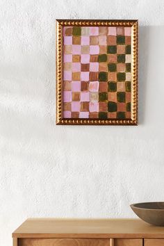 a brown bowl sitting on top of a wooden table next to a wall mounted painting