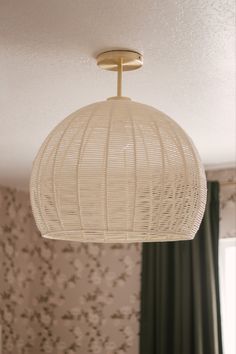 a white lamp hanging from the ceiling in a room with floral wallpaper on the walls