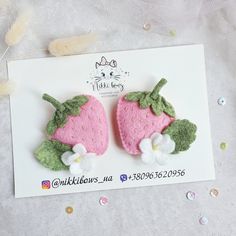 two felt strawberrys with green leaves and white flowers