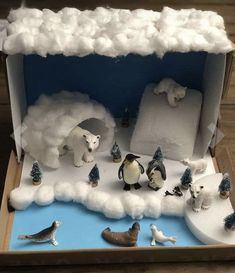 an open cardboard box filled with fake animals and snow