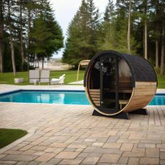 a wooden barrel sitting on top of a brick patio next to a swimming pool in the middle of a park