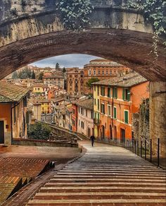 an arch in the middle of a street with stairs leading up to it and buildings on both sides